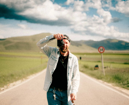 Ritratto di Stefano Vensi, fotografo di matrimonio, che guarda l'obiettivo con la sua fotocamera